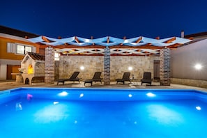A swimming pool with lounge chairs and a brick fireplace. - Villa Mendula Zadar Villas (Novigrad)