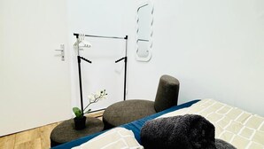 A modern bedroom with a bed, a small potted plant, a round stool, and a wall-mounted mirror. - Cozy Rooms Superb Location near Augarten (Vienna)