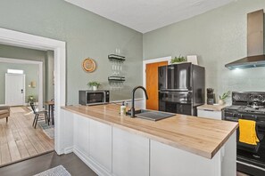 Una cocina moderna con una isla de madera, electrodomésticos de acero inoxidable y una distribución de armarios blancos.