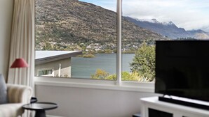 Une pièce dotée d’une grande fenêtre donnant sur un lac, des montagnes et une petite ville.