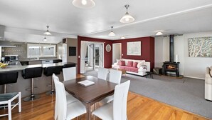 Un salon moderne avec un coin repas, une cheminée et une cuisine en arrière-plan.