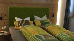 Uma cama com cabeceira verde, várias almofadas e um cobertor listrado.