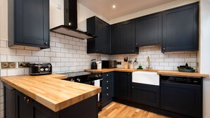 A modern kitchen with dark cabinetry, a wooden countertop, a stove, and a dishwasher. - Dalgety, Peebles - sleeping 8 guests in 4 bedrooms (Peebles)