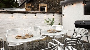 An outdoor patio with round tables and metal chairs, a small potted plant, and string lights. - Dalgety, Peebles - sleeping 8 guests in 4 bedrooms (Peebles)