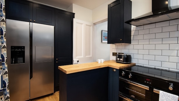 A modern kitchen with a stainless steel refrigerator, a wooden countertop, a black range hood, and a black oven. - Dalgety, Peebles - sleeping 8 guests in 4 bedrooms (Peebles)