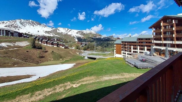 Ein Bergresort mit Blick auf schneebedeckte Gipfel, einen Fluss und ein Holzbauten mit Balkonen.