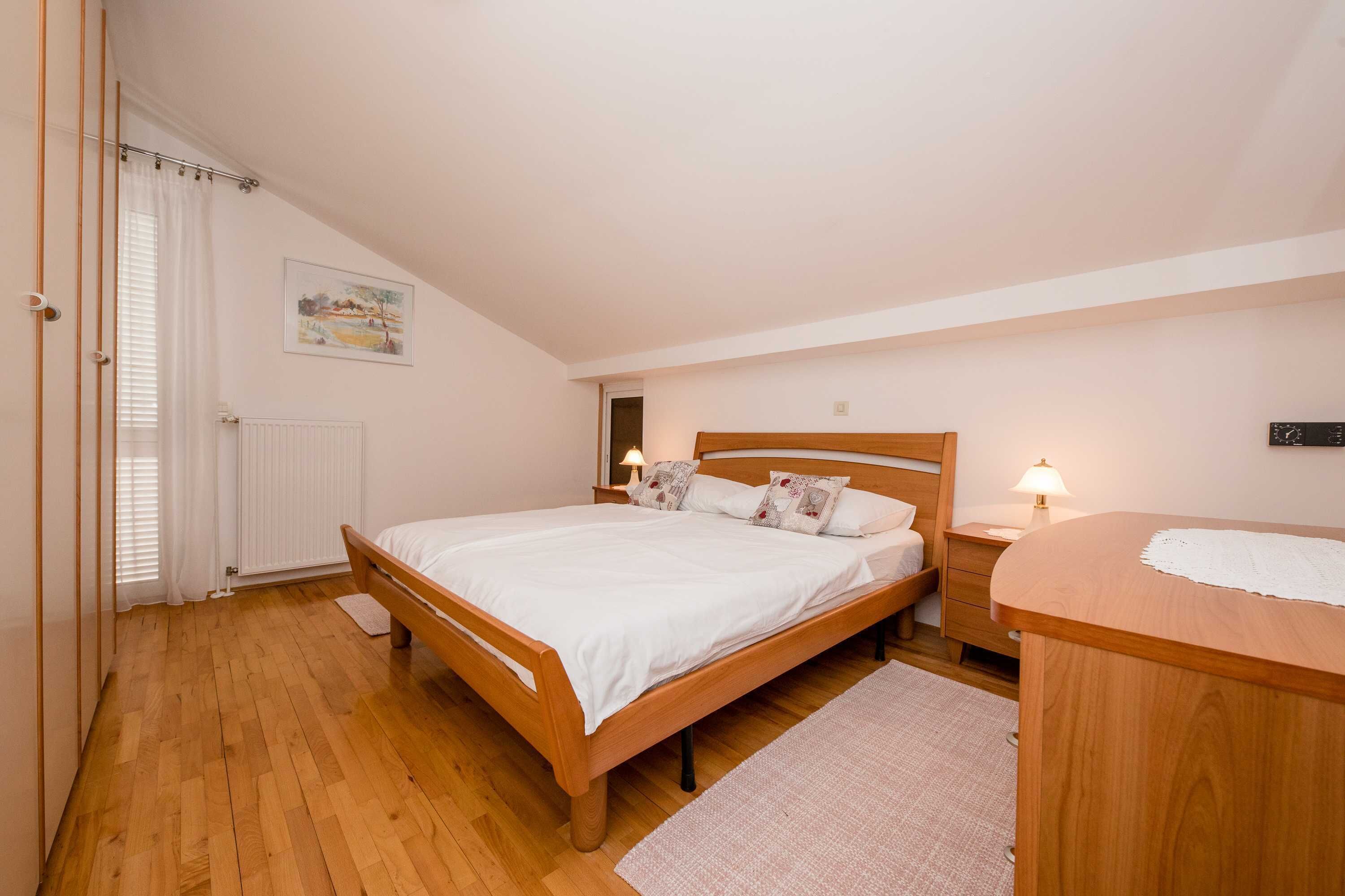 Ein Schlafzimmer mit einem hölzernen Bett, Nachttischen, einem Heizkörper und einem Bild an der Wand.