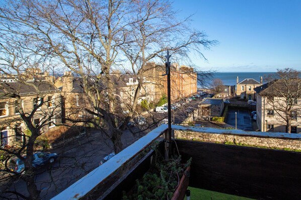 A view of a coastal town with historic buildings, a railway track, and a clear sky.