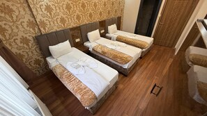 A hotel room with three beds, a patterned wallpaper, and a wooden floor. - FORTYNINE HOTEL (Istanbul)