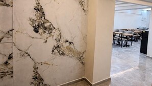 Un intérieur moderne avec des murs en marbre, un sol carrelé et un espace détente comprenant des tables et des chaises.