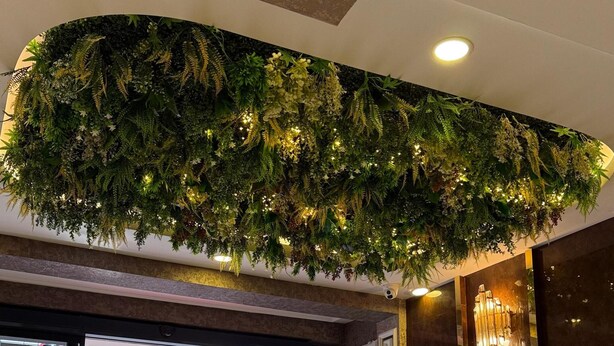 Un hall d’entrée agrémenté d’un mur végétal artificiel, d’une plante en pot et d’un sol réfléchissant.