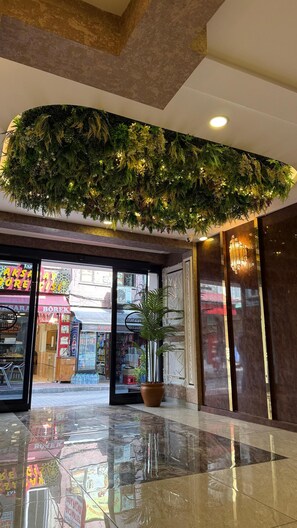 A lobby with a green artificial plant wall, a potted plant, and a reflective floor. - FORTYNINE HOTEL (Istanbul)