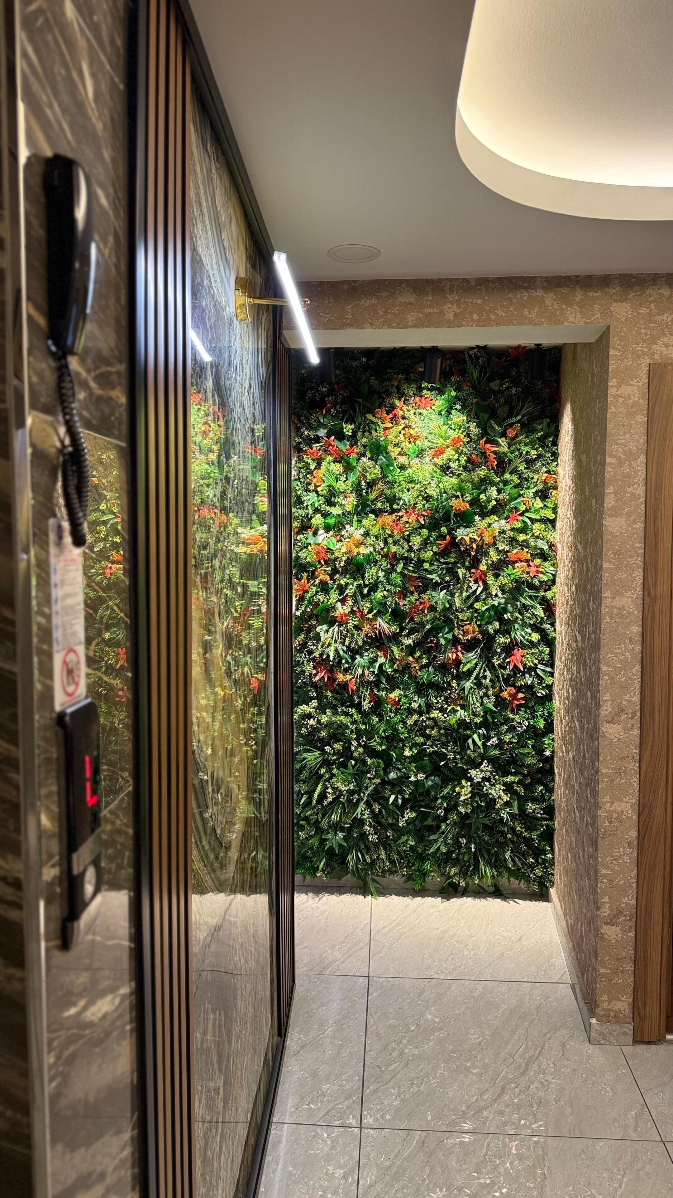 Un passadís amb una porta de vidre que dona a una habitació amb un paper pintat de flors i un telèfon a l'esquerra.