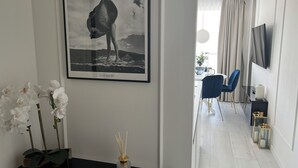 A modern living room with a framed photograph on the wall, a vase with white orchids, and a black side table. - Apartament Glamour z basenem - 365PAM (Kolobrzeg)