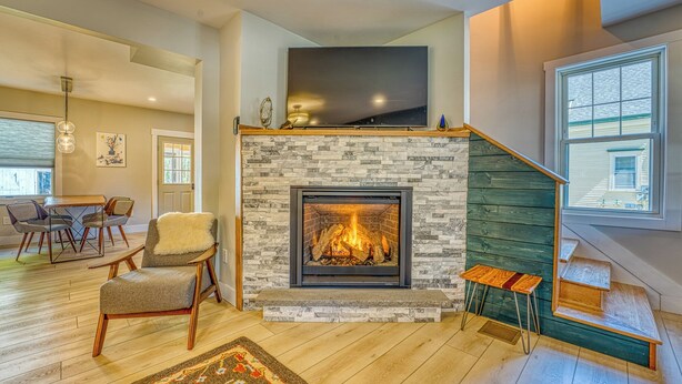 Una sala de estar moderna con chimenea, piso de madera y una escalera.