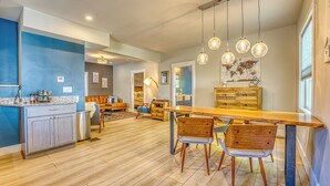 Una cocina moderna con suelo de madera, una isla central e iluminación colgante.