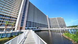 Un hotel moderno con varios pisos, vista al agua y un paseo marítimo de madera.