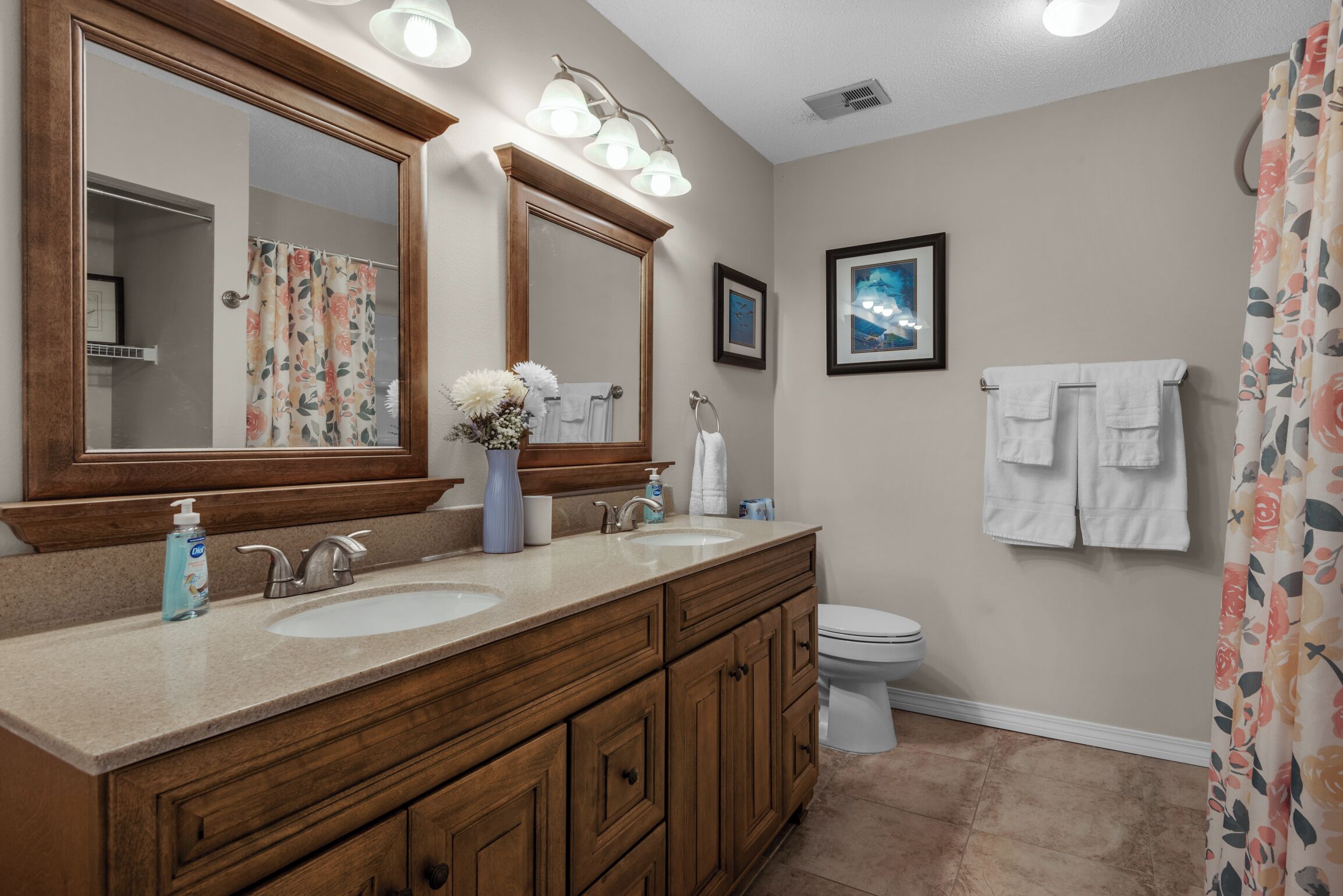 Une salle de bain avec deux lavabos, des toilettes et une douche.