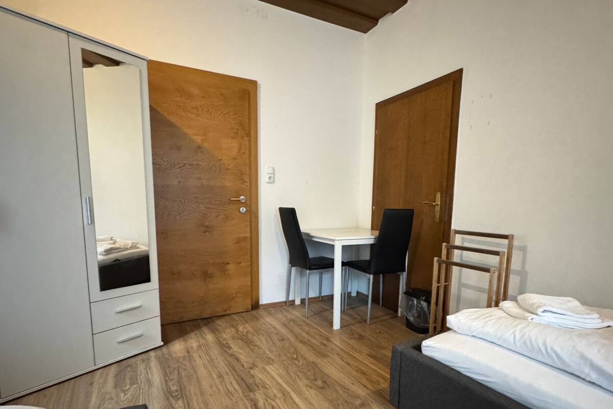 A compact bedroom with a bed, a desk, and a wardrobe.
