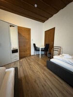 Un dormitorio pequeño con cama, escritorio y armario.