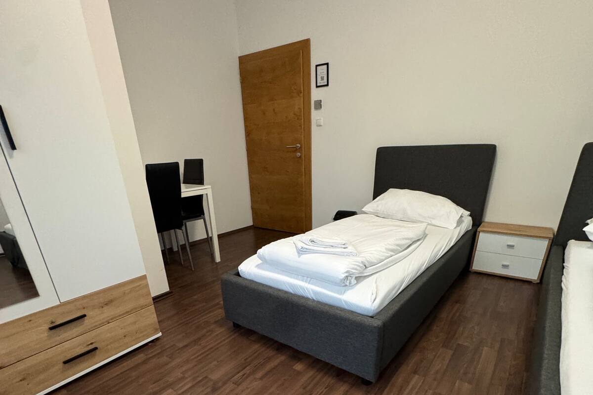 A modern bedroom with a bed, a desk, and a wardrobe.
