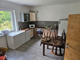 Una cocina compacta con ventana, microondas, lavamanos y una mesa de madera con sillas.
