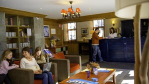 A lobby with a reception desk, seating area, and bookshelves. - 50m from ski slopes, balcony, tv, ski locker, 30m², Valloire (Valloire)