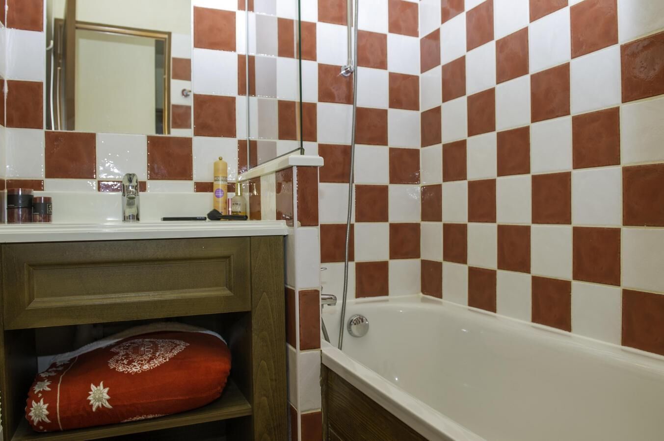 A bathroom with a checkered tile pattern, a bathtub, a shower, and a vanity with a mirror.