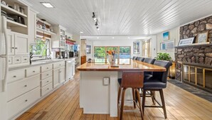 A spacious kitchen with white cabinetry, a wooden island with bar stools, and a stone fireplace. - 3-story lake front views! Dock, Hotspring spa, outdoor dining, watch our video! (Gray)