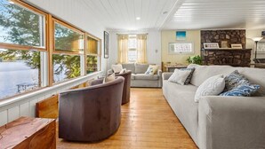 Een knusse woonkamer met een groot raam, een stenen openhaard en een houten vloer.