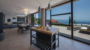 A modern living room with a dining area, large windows, and a view of the sea. - Villa The View Opatija Nearby Rijeka - Crovillas (Opatija)