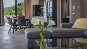 A modern living room with a sofa, a glass coffee table, and a vase with white flowers. - Villa The View Opatija Nearby Rijeka - Crovillas (Opatija)