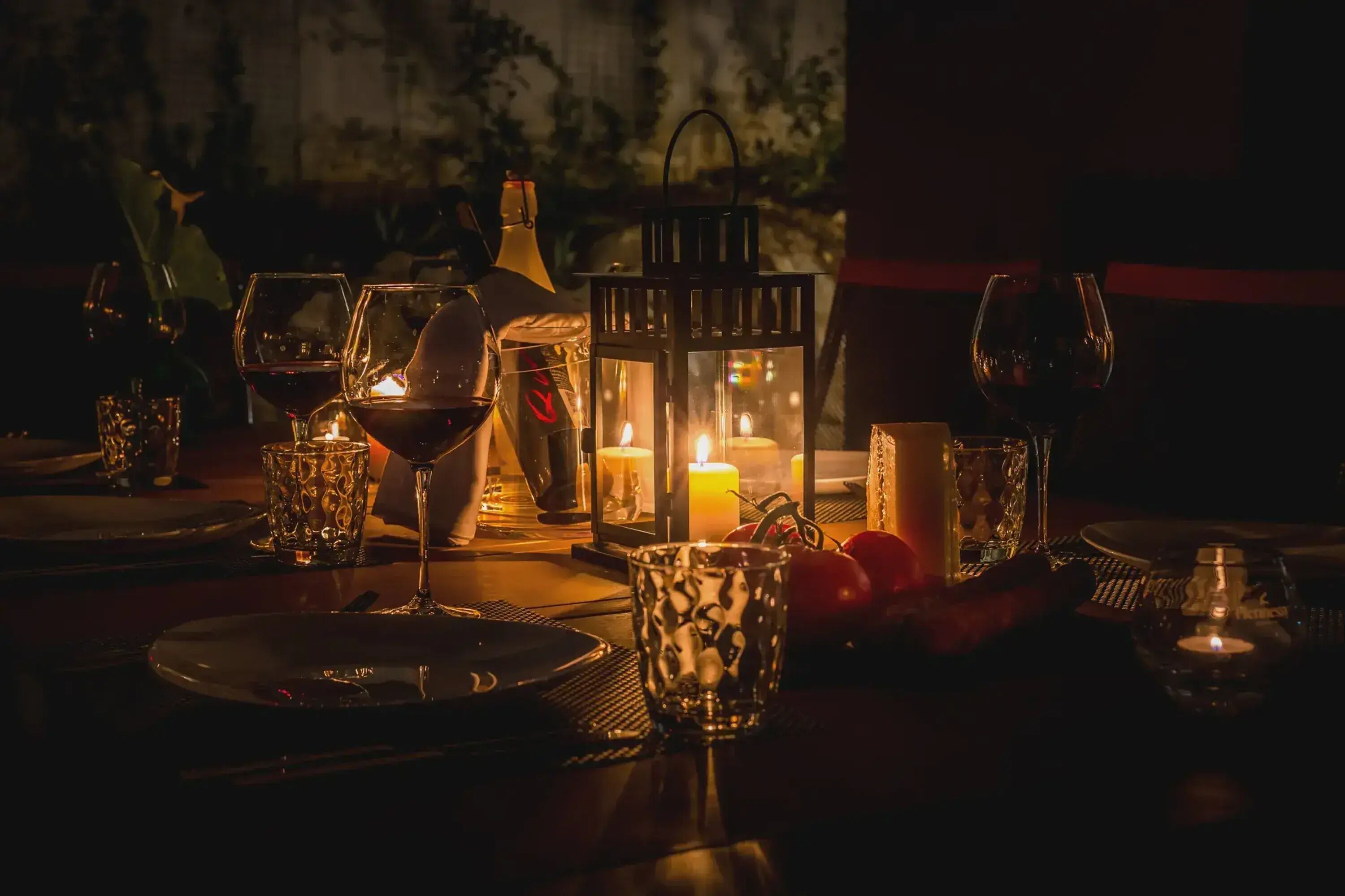 A dimly lit dining area with candlelight, wine glasses, and a lantern.
