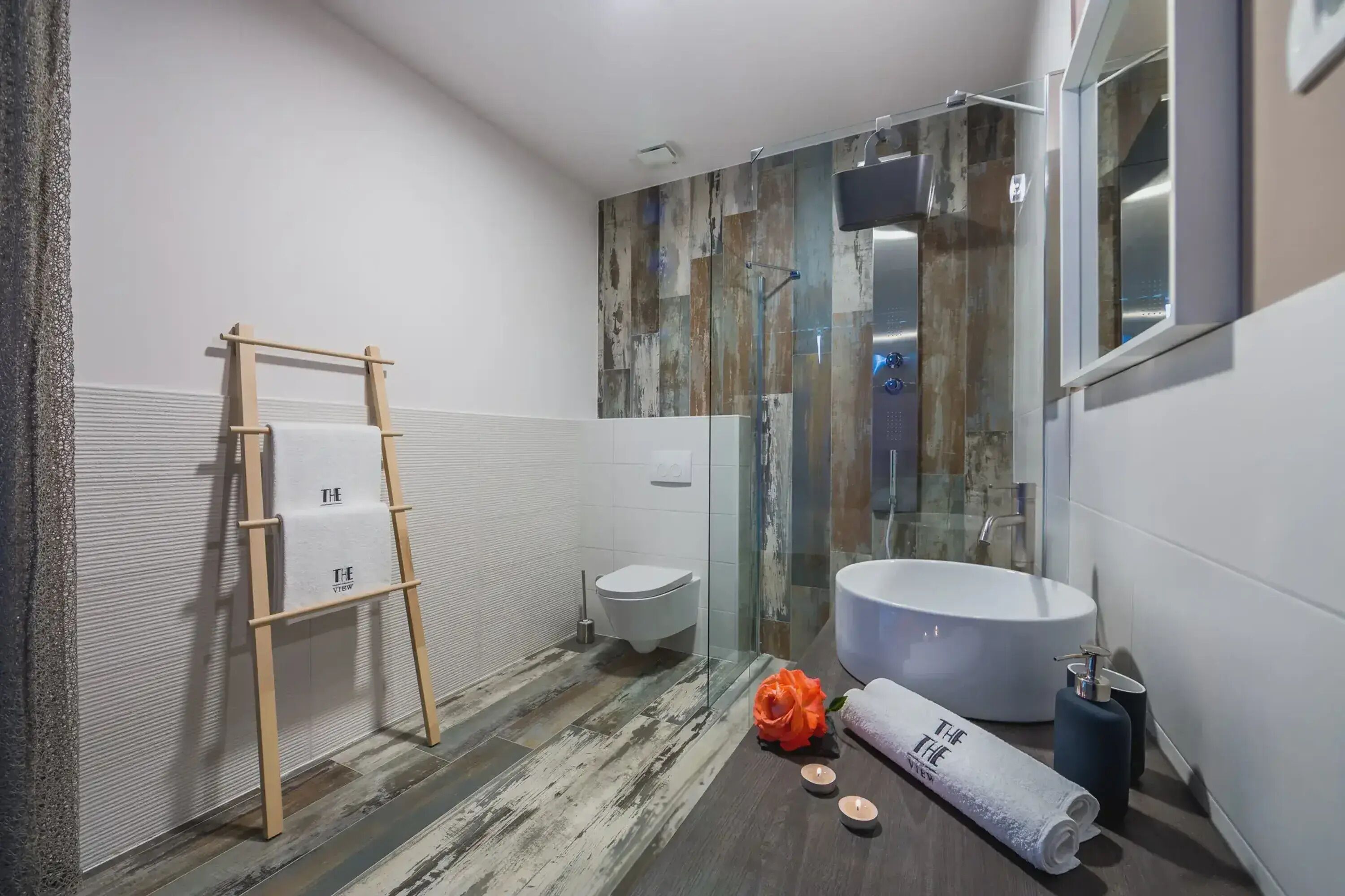 Une salle de bain moderne avec une échelle en bois, un lavabo blanc et une cabine de douche en verre.