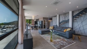 A modern living room with a sectional sofa, a glass coffee table, and a dining area in the background. - Villa The View Opatija Nearby Rijeka - Crovillas (Opatija)
