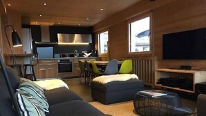 Kompakti oleskelutila, jossa on sohva, rahi, ruokailualue ja pieni keittiö.