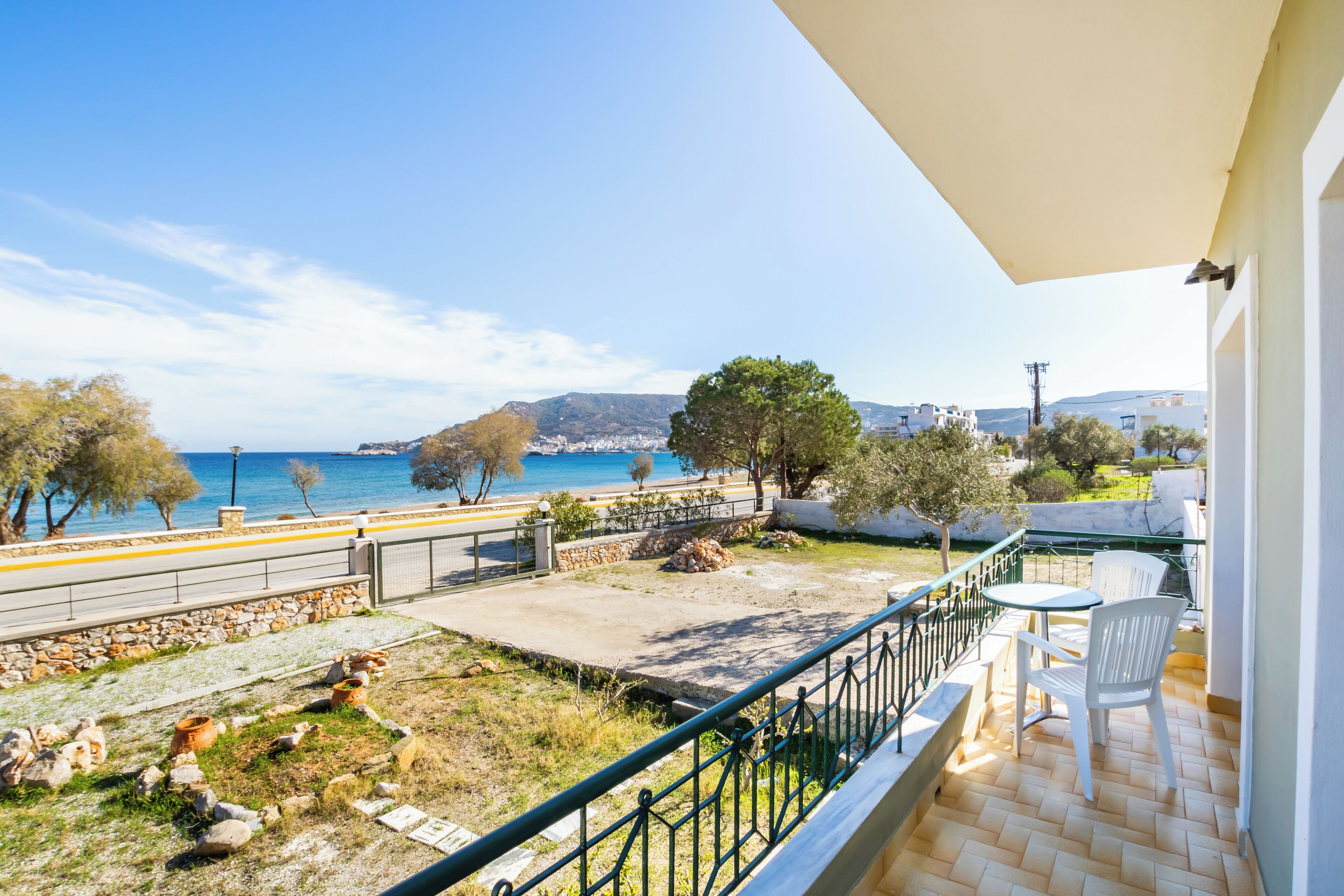 A balcony with a view of the sea, a stone pathway, and a small garden area.