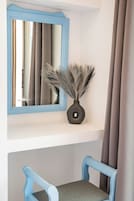 A room with a blue-framed mirror, a vase with dried plants, and a blue chair.