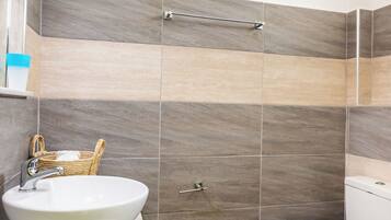 A bathroom with a white sink, a toilet, and a shower area.