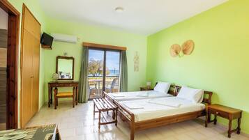 A bedroom with two beds, a desk, a chair, and a balcony with a view.