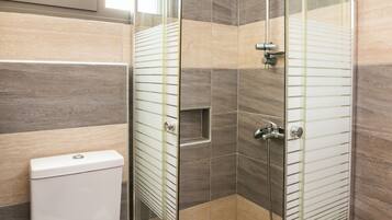 A modern bathroom with a glass-enclosed shower, a toilet with a towel, and a window above the sink.