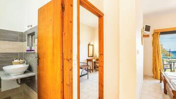 A hotel bathroom with a sink, mirror, and wooden door.