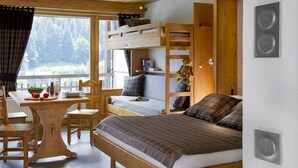 Una habitación acogedora estilo cabaña, con una cama litera, un escritorio de madera con silla, y ventana con vistas a un área boscosa.