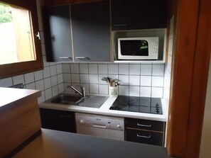 A compact kitchen with a microwave, sink, and dishwasher.