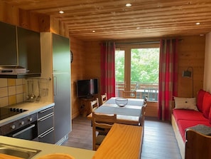 A cozy cabin interior with a kitchen, dining area, and a red sofa.