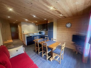 A cozy cabin interior with a dining area, kitchen, and a TV.