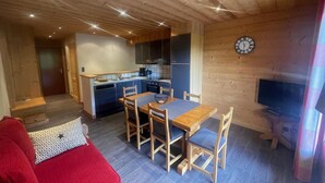 Ein gemütliches Blockhauss-Interieur mit Essbereich, Küche und Fernseher.