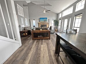 Un salón amplio con chimenea, un ventanal grande y un ventilador de techo.