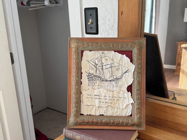 Una obra de arte enmarco con un barco y una cita, sobre una pila de libros.