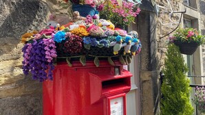 A red post box with colorful crocheted flowers and a sign for Ginger Plum Coffee Shop. - The Old Middle School 1700 Cottage Addingham (Addingham)